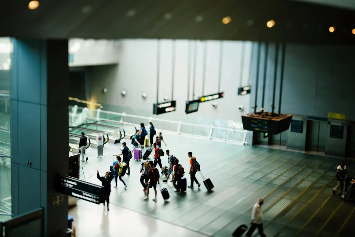 A group of travelers pulling suitcases across an airport concourse